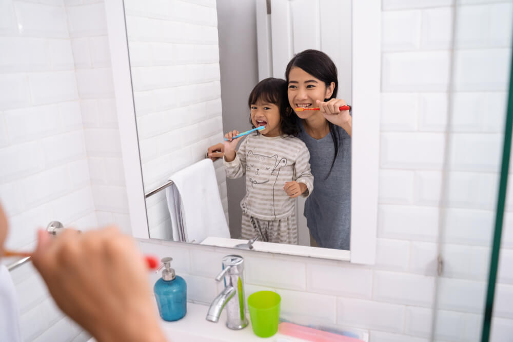 happy attractive mom and kid brushing their teeth together