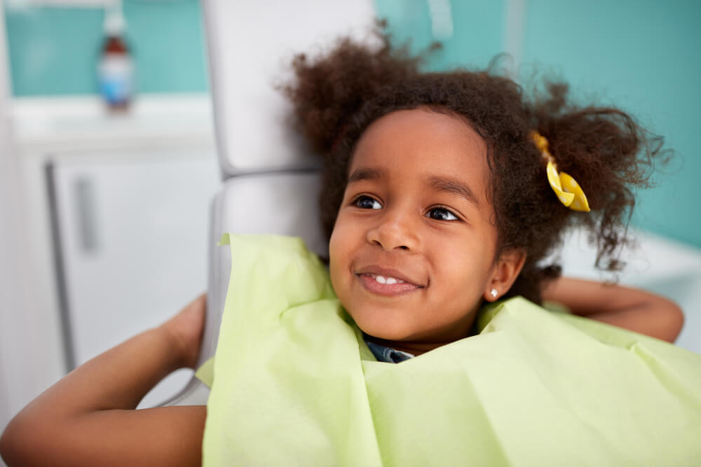 satisfied child in dental chair after successful dental treatment